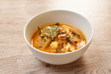 spicy boiled mussel with pineapple and lemon leaf in coconut milk curry soup on bowl
