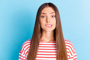 Photo of pretty unsure young girl wear striped shirt biting lip isolated blue color background