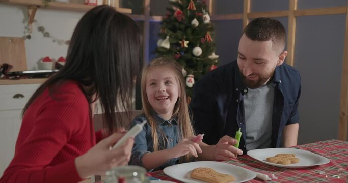parents play with their daughter and help paint gingerbread