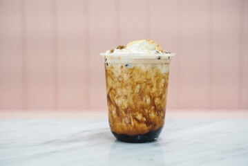 Iced Espresso bubble drink. A plastic cup of espresso blended with milk and topped with bubble/boba pearls, brown sugar syrup, cream cheese and jelly.