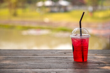 Red drink with ice cubes in a glass, Red soda in glass put on wooden table