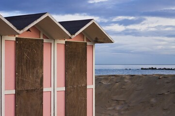 Pink beach cabins in the bathhouse on the sand with Mediterranean sea in background (Pesaro. Italy, Europe)
