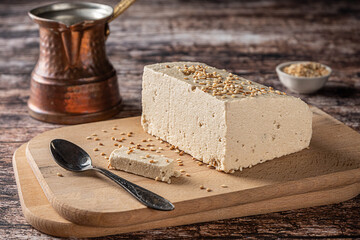 Tahini halva, with sesame seeds as its main ingredient, and a cezve on vintage wooden background