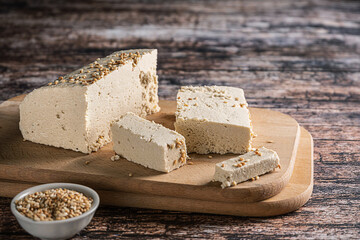 Sliced tahini halva on wooden background, with sesame seeds as its main ingredient