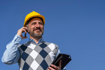 Portrait of Smiling Manager with Mobile Phone and Digital Tablet Against The Blue Sky