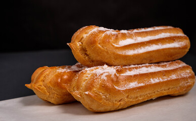 Eclairs with cream on a dark background