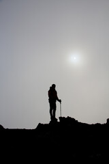 Sagoma di un escursionista in alta montagna con il sole alle spalle