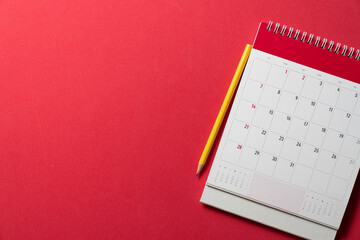 close up of calendar and yellow pencil on the red table background, planning for business meeting or travel planning concept - obrazy, fototapety, plakaty