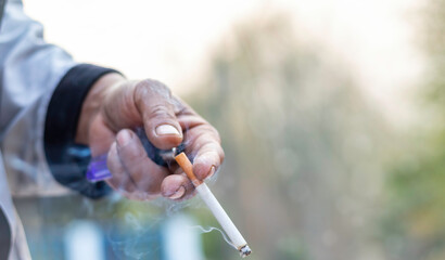 man holding smoking a cigarette in hand. Cigarette smoke spread.