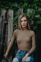 Blonde woman sits near wooden fence and elderberry shrub.