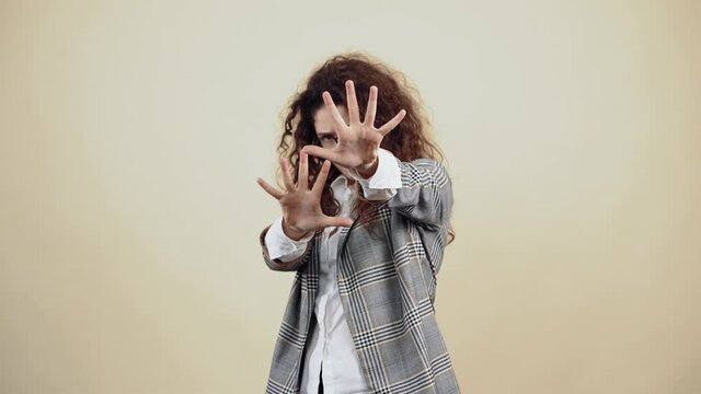The 20-year-old says stop with both hands in front. Cretaceous in gray jacket and white shirt, with glasses posing isolated on a beige background in the studio. The concept of people's lifestyle.