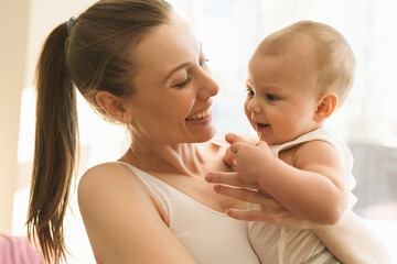 Mother and baby close-up. Mom holds the child in her arms, hugs him and kisses him. Happy family concert