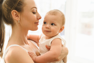 Mother and baby close-up. Mom holds the child in her arms, hugs him and kisses him. Happy family concert