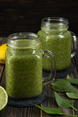 Healthy green smoothie with spinach in glass jars.