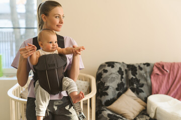 Portrait of a young mother with a child in a child carrier. The Happiness of Motherhood Concept