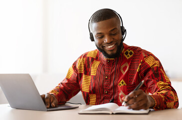 Online Learning. Black Man In African Clothes Study With Laptop At Home