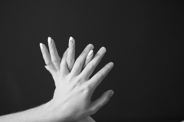 A loving couple holding hands. Against a dark background. And wedding rings on my hands.