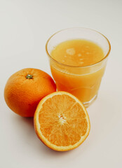 Vaso de zumo de naranja con una naranja y media