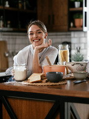 Portrait of young woman in the kitchen. Happy smiling woman baking at home..