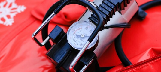 Electric pump with monometer pumping air into tire of tube on winter day. Equipment, device.	