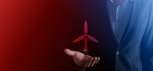 Businessman holding an icon of a windmill that produces environmental energy. Dark background. Neon red , blue light