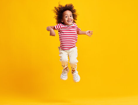 Active Positive Black Kid Jumping Against Blue Background