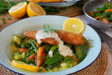 Fish dish with vegetables, potatoes and sauce on a plate