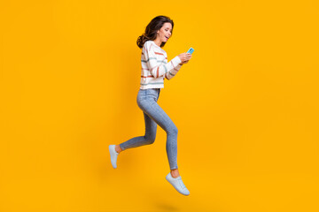 Fototapeta na wymiar Full body profile side photo of young excited girl happy smile jump up chat type use cellphone isolated over yellow color background