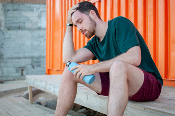 Portrait of a young and masculine man drinking water outside after a train at gym. Relax after running.  