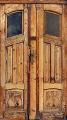 Old worn door of wood with windows damaged and ornaments with ancient texture from an abandoned building	
