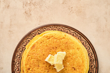 Crepes or thin pancakes stack with butter and red caviar on beautiful ceramic plate on an old brown concrete background. Top view, copy space. Homemade thin crepes for breakfast or dessert.