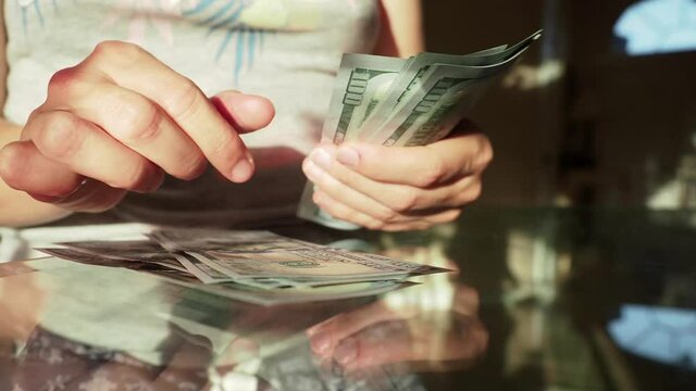 World economic crisis. Total unemployment in a pandemic. Housewife hands holding US money banknotes of new 100 dollars and count american dollars cash money. Closeup