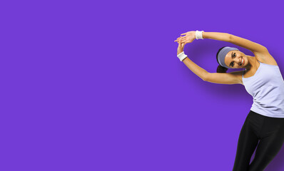 Happy smiling african american woman in sportswear doing stretching fitness exercise or yoga moves, isolated over violet purple background. Sporty girl at studio. Copy space empty area for some text