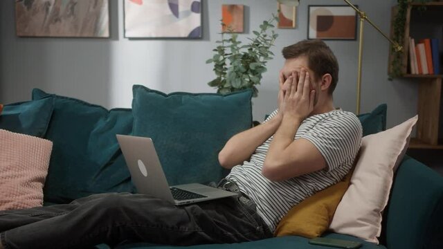 Portrait of tired man sitting at sofa and working remote on computer desktop in cozy room at day, Work hard and too concetration, home freelance, coding new programm, daylight, professional employee 