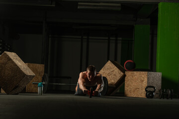 Shirtless pro athlete doing russian twist abs workout. Close up photo of a fit male athlete doing indoor training.