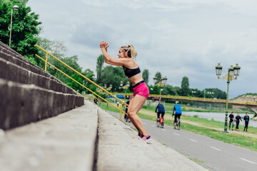 Fototapeta premium Fit healthy athlete, beautiful woman in tight sportswear jumping on stairs, warming up before jogging while looking highly motivated..