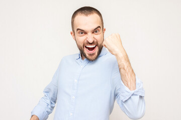 Fototapeta premium Attractive bearded rejoices in the victory and shouts: Hooray! Portrait, white background