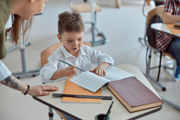 Happy kind teacher is helping kids in elementary school lessons