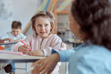 Happy kind teacher is helping kids in elementary school lessons