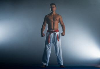 Fototapeta na wymiar One judoka fighter man in kimono practicing in the gym