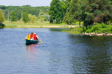 Fototapeta na wymiar family canoeing in pond in summer sun