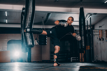 Fototapeta premium Angry muay thai fighter practicing punch on punching bag