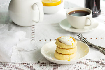 Cottage cheese pancakes with sour cream and lemon zest, served with tea.
