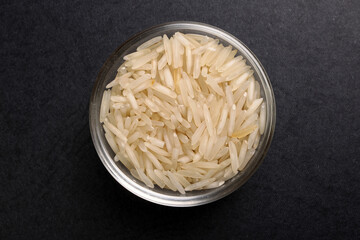 Long grain basmati rice in glass bowl on black background