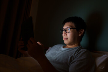 Fototapeta na wymiar Asian man between the ages of 35 and 40 plays a laptop in his bed. Concept of technology, poor health, insufficient rest