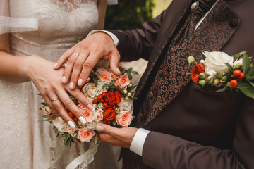 The bride and groom put their hands on the wedding decorative bouquet of flowers of roses close-up