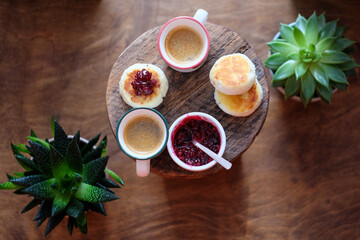 Syrniki with lingonberry jam and coffee top view on a wooden background. 
Cheese pancake.