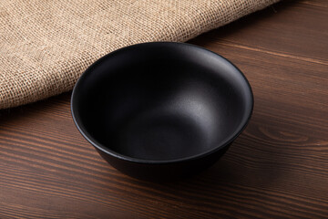 Empty black ceramic bowl isolated on wooden background. Close-up