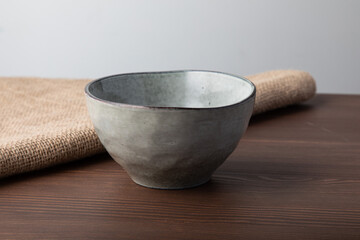 Empty hand made light gray bowl. Isolated on wooden background