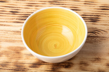Empty white bowl with hand painted yellow inside. Isolated on wooden background